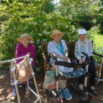 our care home residents sitting on a bench beside a green hedge