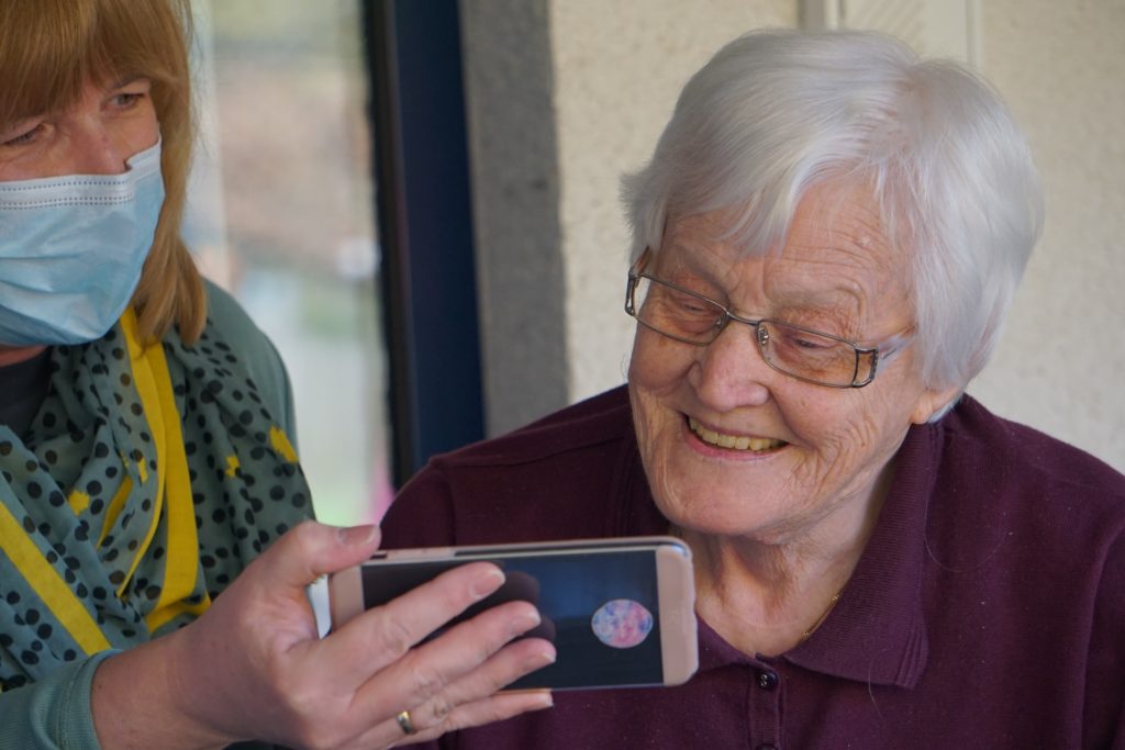 elderly woman looking at phoen at a care home