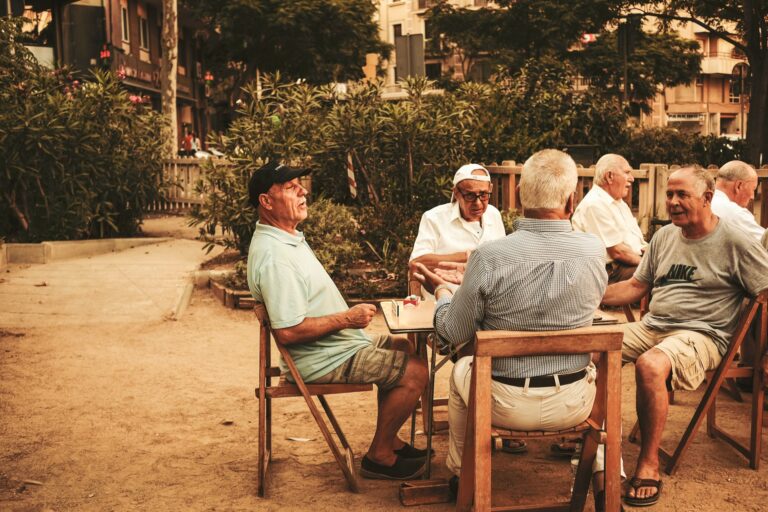 four elderly men sitting around a table outside