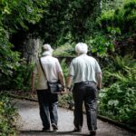 two elderly people walking through trees