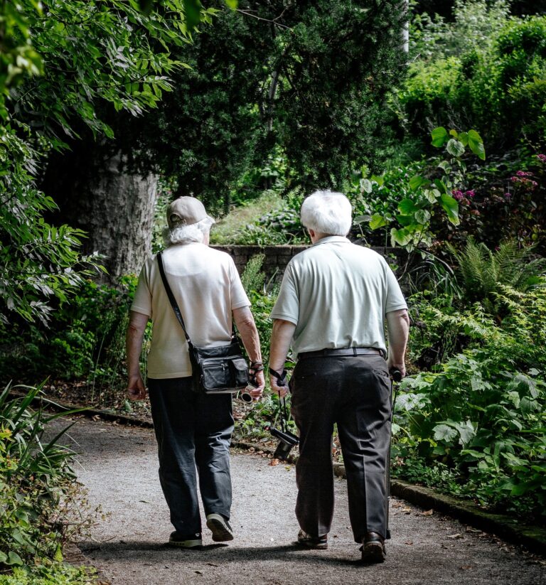 two elderly people walking through trees