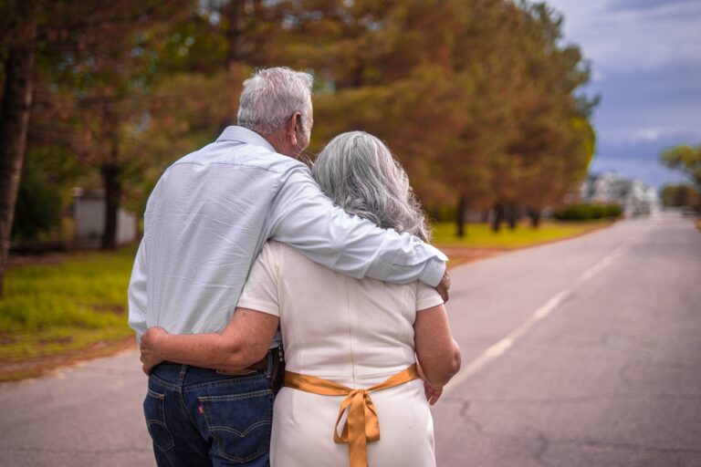 elderly couple walking down road together
