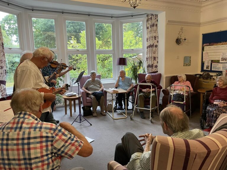 care home residents gathering around listening to music