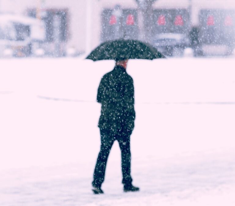 man walking in snow with umbrella