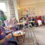 elderly people and carer knitting together