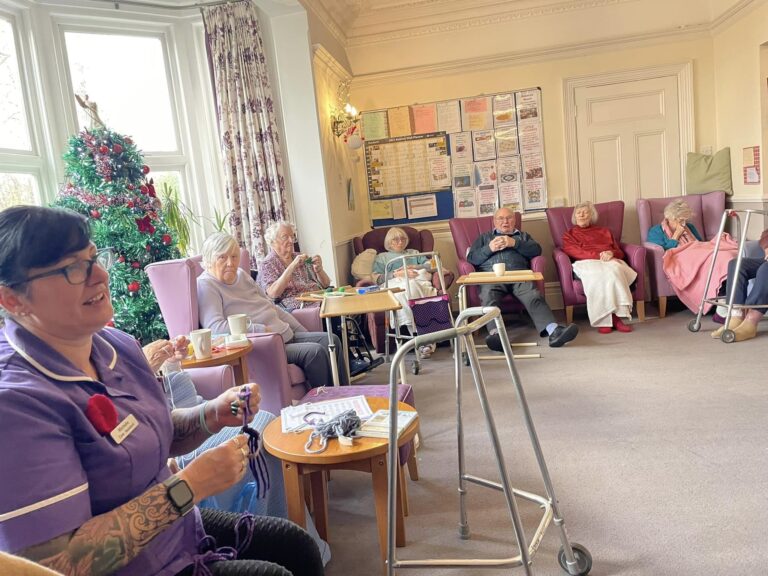 elderly people and carer knitting together