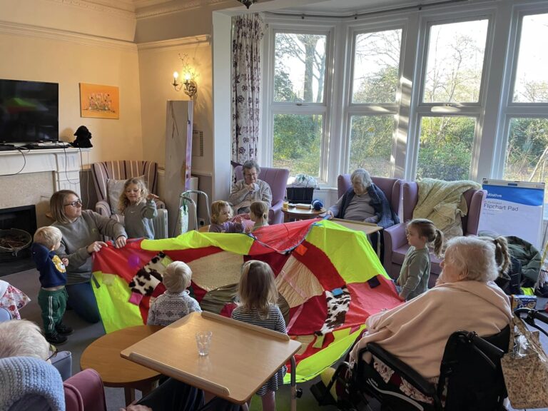 children and care home residents playing with a coloured parachute