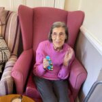 A redisent at the Hilgay Care Home sitting in a chair smiling