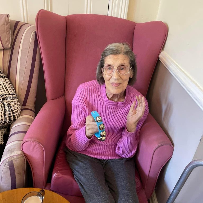 A redisent at the Hilgay Care Home sitting in a chair smiling