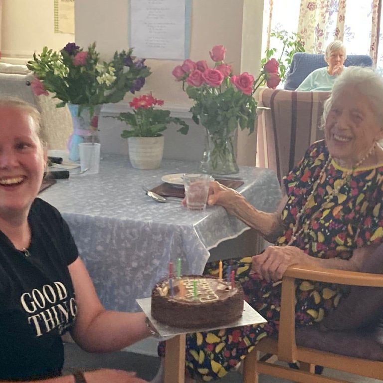 care home carer giving cake to elderly resident