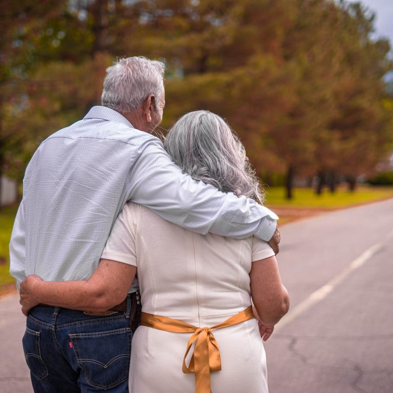 elderly couple walking down road together