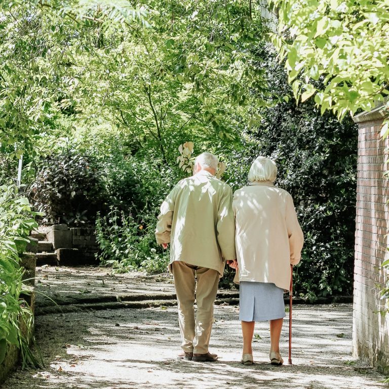 elderly couple walking among trees