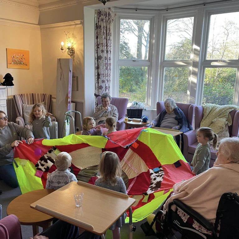 children and care home residents playing with a coloured parachute